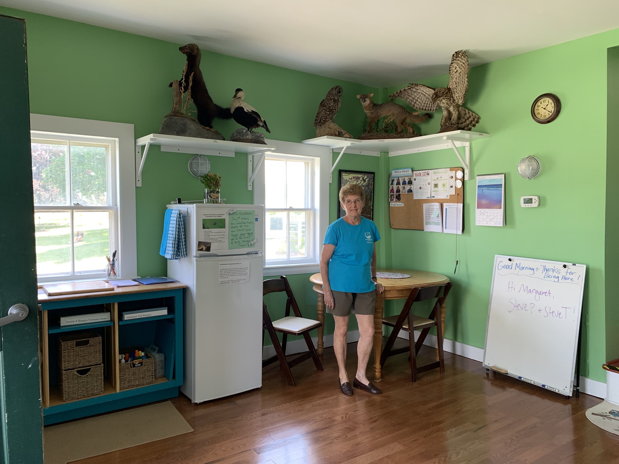 Volunteer Carolyn Broad and the walls she painted "picnic" green for the docent room remodel. Photo by Amy Maden.