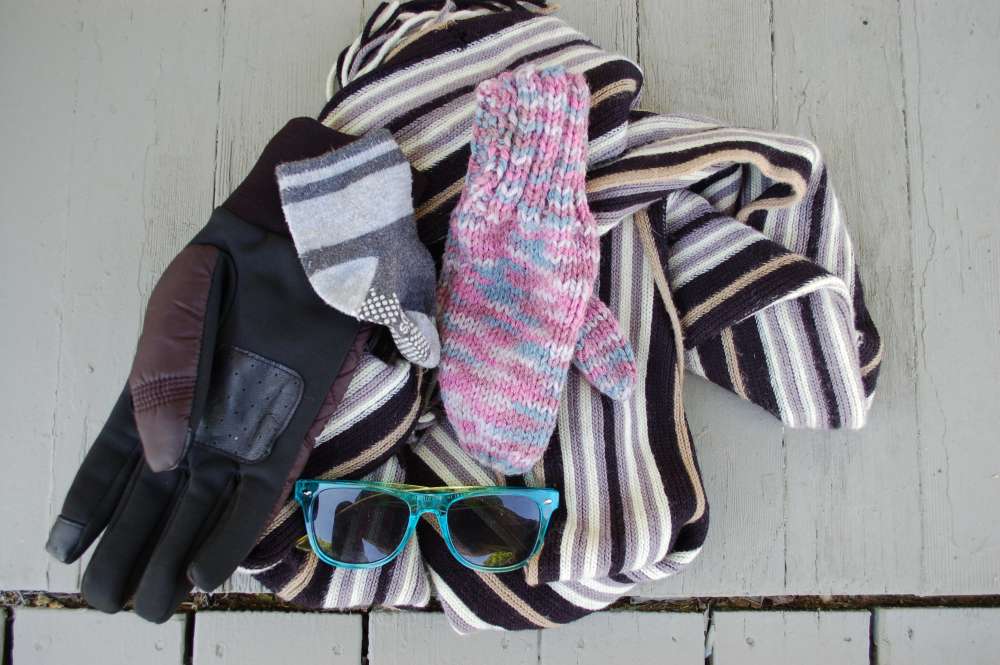 Jumble of lost items including mitten, scarf, glove, sunglasses, sock.
