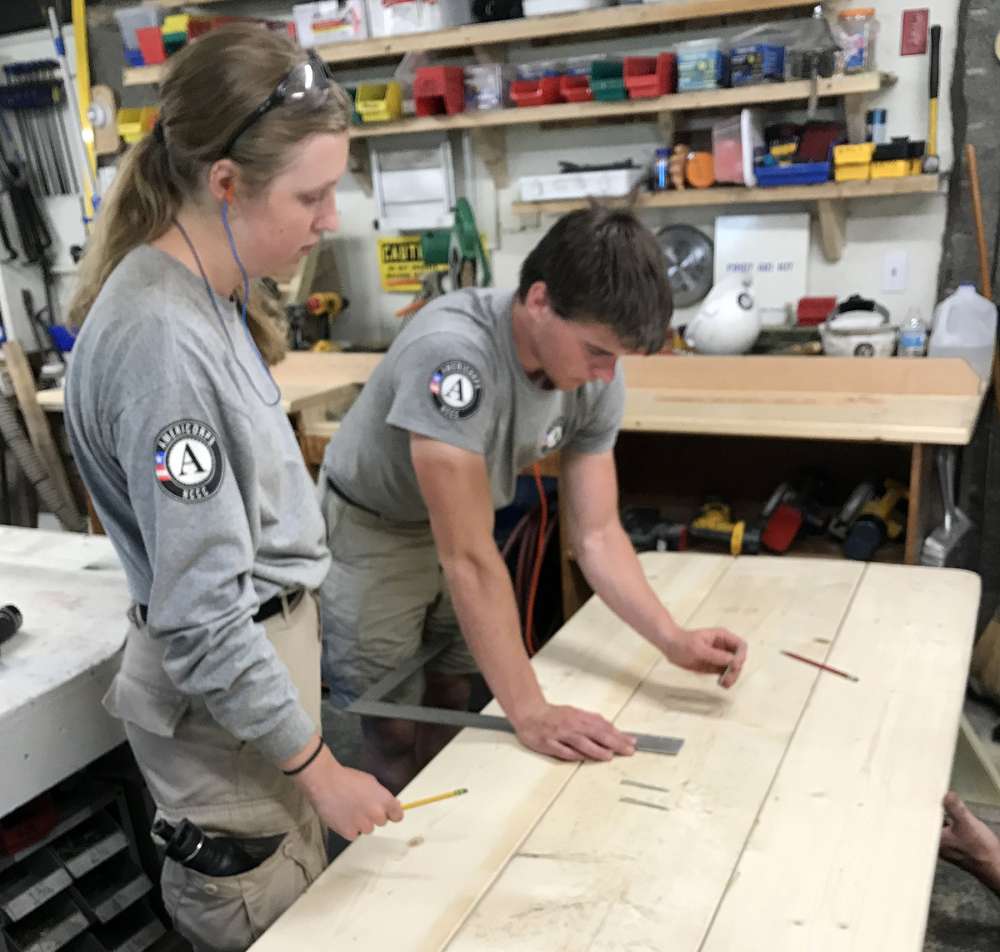 AmeriCorps volunteers mark a picnic table.