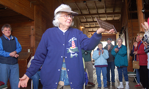June Ficker shows off the plaque that dedicates the Saw-whet Trail in her name, May 2015.