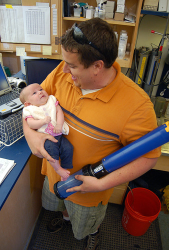 Jeremy Miller holds daughter Camille and water testing instrument in the research lab.